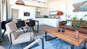 A modern living room with a dining area, a kitchen, and a staircase. - Cube Exclusive 6 (Nieuwvliet)