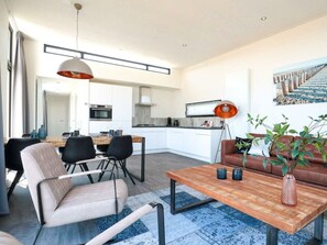 A modern living room with a dining area, a kitchen, and a staircase. - Cube Exclusive 6 (Nieuwvliet)