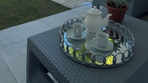 Une terrasse avec une table préparée pour le thé, entourée de fauteuils et de palmiers.