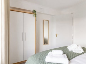Ein Hotelzimmer mit Bett, einem Schrank, einem Spiegel und einer grünen Strickdecke.