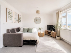 Ein Schlafzimmer mit einem Bett, einem Fernseher, einem Nachttisch, einem Spiegel und einem Fenster mit Blick.