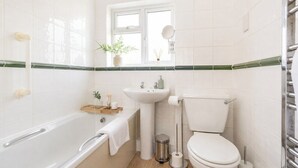 Un baño con bañera, lavamanos, inodoro y ventana.