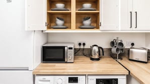 Ett kök med vita skåp, en mikrovågsugn, en kaffebryggare, en brödrost och en diskmaskin.