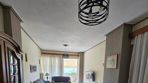 A spacious living area with a dining table, sofa, and a large cabinet. - Kons Beach Front Apartment with Sea View, Wi-Fi, and Air Conditioning (Kalamata)