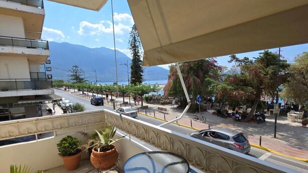 A balcony with potted plants, a table, and a chair. - Kons Beach Front Apartment with Sea View, Wi-Fi, and Air Conditioning (Kalamata)
