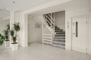 A clean, modern interior with a staircase, white walls, and potted plants. - Kons Beach Front Apartment with Sea View, Wi-Fi, and Air Conditioning (Kalamata)