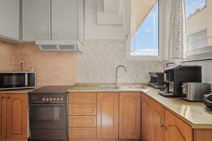 A kitchen with a microwave, stove, sink, and coffee maker. - Kons Beach Front Apartment with Sea View, Wi-Fi, and Air Conditioning (Kalamata)
