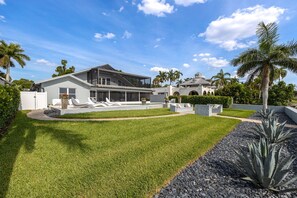 Une maison moderne dotée d’une grande pelouse, d’une piscine et d’un jardin bien entretenu.