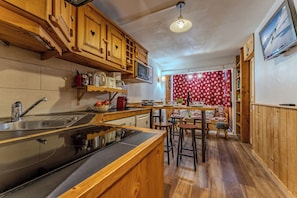 Una cocina con armarios de madera, una estufa, un fregadero y una zona de comedor con taburetes.