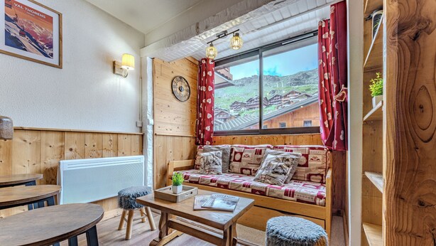 Un cuarto acogedor con un banco de madera, una mesa y una ventana que ofrece vistas a un pueblo.