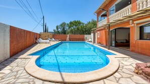 A rectangular swimming pool with a tiled edge, surrounded by a stone deck.