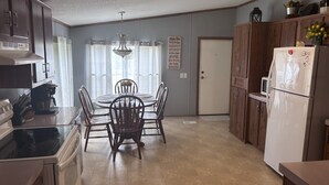 Una cocina con una mesa de comedor, sillas, un refrigerador y armarios.