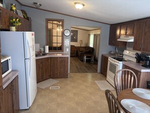 Une cuisine de taille réduite, dotée de meubles de rangement en bois, d’un réfrigérateur, d’un four à micro-ondes et d’une cuisinière.