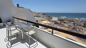 A balcony with a table and chairs, overlooking a coastal town and the sea. - Sunset View Albufeira 53 (Albufeira)