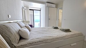 A bedroom with a bed, a nightstand, a window with curtains, and a door leading to a balcony. - Sunset View Albufeira 53 (Albufeira)