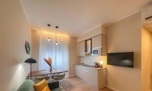 Ein kompakter Wohnbereich mit Küchenzeile, Essplatz und einem an der Wand befestigten Flachbildfernseher.