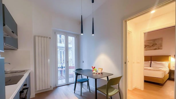 Een ruimtelijk ingerichte leefruimte met kitchenette, eethoek en slaapkamer.