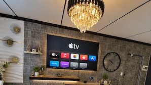 Una sala de estar moderna con un televisor de pantalla plana montado en la pared, una araña y un reloj.