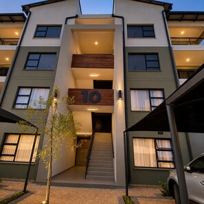 A multi-story building with a central staircase, numbered 10, and a car parked in the driveway.
