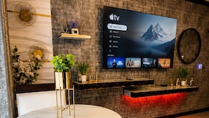 Una sala de estar moderna con un televisor de pantalla plana montado en la pared, una mesa de comedor redonda y un sofá.