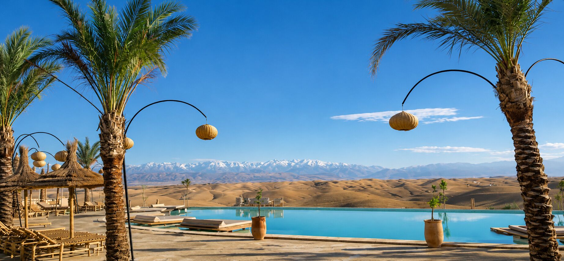 A pool area with lounge chairs, palm trees, and a mountain view.