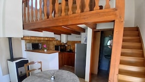 A kitchen with a wooden staircase, a dining table with chairs, and a view of the living area.