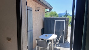 An open door leading to a patio with a table and chairs, a closed door, and a view of a mountain.