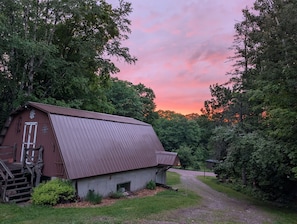 A rustic barn with a sloped roof, a wooden staircase, and a gravel path leading to it. - Northwoods Trails - State Forest Retreat (Gwinn)