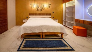 Un dormitorio con cama, mesitas de noche, una lámpara de pared, armario empotrado y un pequeño taburete naranja.
