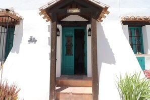 A white building with a turquoise door, a wooden porch, and a 'Welcome Home' sign. - 1095 Casa Nido del Buho (Cómpeta)