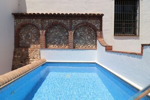 A swimming pool with stone arches and a window with bars. - 1095 Casa Nido del Buho (Cómpeta)