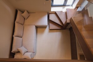 A modern interior with a sectional sofa, a staircase, and a skylight. - Lovely 1-bedroom duplex apartment in the heart Saranda - Solvèa Apartments 104 (Saranda)