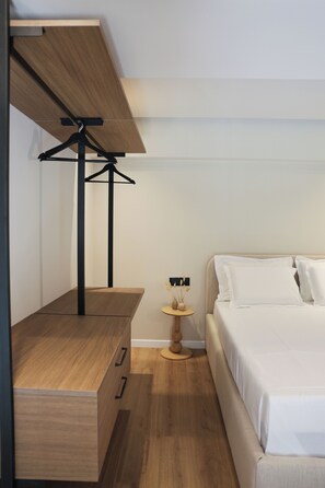 A bedroom with a bed, a wooden dresser, a hanging light fixture, and a small round table with a vase. - Lovely 1-bedroom duplex apartment in the heart Saranda - Solvèa Apartments 104 (Saranda)