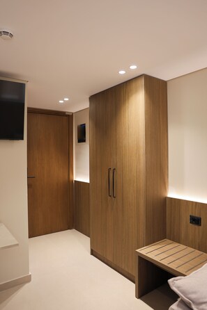 A modern room with a wooden wardrobe, a small bench, and a flat-screen TV mounted on the wall. - Lovely 1-bedroom duplex apartment in the heart Saranda - Solvèa Apartments 104 (Saranda)