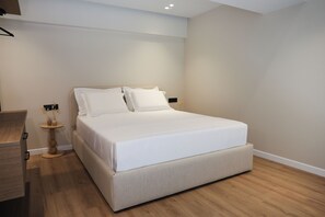 Une chambre moderne avec un grand lit, des tables de chevet et une petite table ronde décorée de bougies.