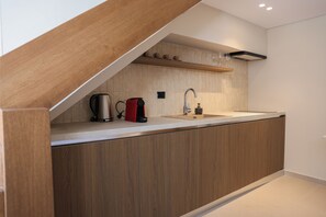 Eine moderne Küche mit einer Holzausziehtheke, einer integrierten Spüle und einer Kaffeemaschine.