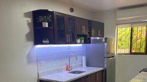 Eine Küche mit dunklen Holzschränken, einer Granit-Arbeitsplatte, einem Glastisch und einer integrierten Spüle.