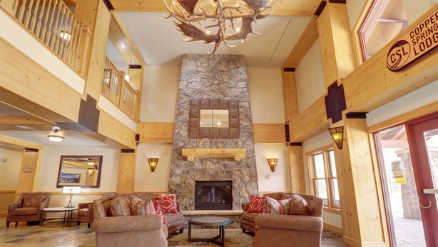 Eine geräumige Lobby mit Kamin aus Stein, Holzmöbeln und einem Schild für Copper Springs Lodge.