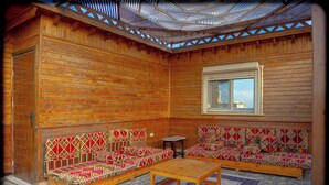 A log cabin interior with a wooden bench, a small table, and a window. - Spacious 2-bedroom apartment with Rooftop between GEM and Giza Pyramids (Giza Governorate)