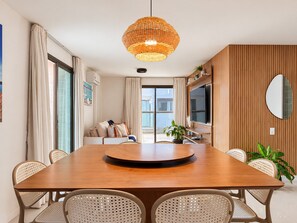 A modern dining area with a wooden table, woven pendant light, and wicker chairs.