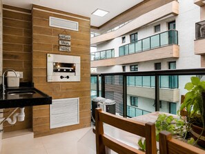 Un apartamento moderno con cocina, un balcón con vista al edificio y una planta en maceta.
