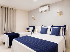 Une chambre d’hôtel avec deux lits, un climatiseur fixé au mur, des lampes de chevet et un téléphone.