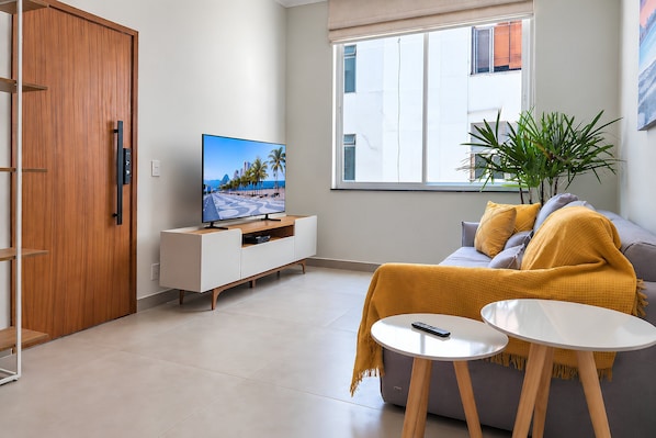A modern living room with a television, sofa, coffee table, and a plant.