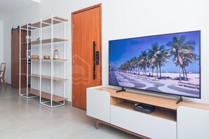Moderni olohuone, jossa on televisio, puuovi, valkoiset hyllyt ja valkoinen kaappi.