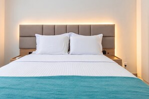 A hotel room with a bed, a headboard, a nightstand, and a bedside table.
