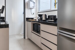 A modern kitchen with a built-in oven, a coffee maker, and a microwave.