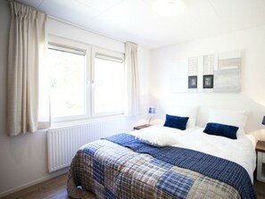 Ein Schlafzimmer mit Bett, Fenster, Heizkörper und einem Wandbild.