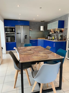 Een moderne keuken met blauwe kastjes, een ingebouwde oven en een koelkast.