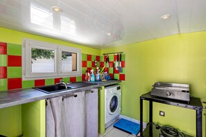 A compact kitchen with a washing machine, a sink, and a window.