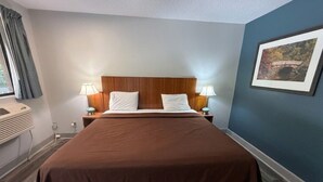Una habitación de hotel con una cama grande, dos lámparas de noche, un cuadro en la pared y una ventana con cortinas.
